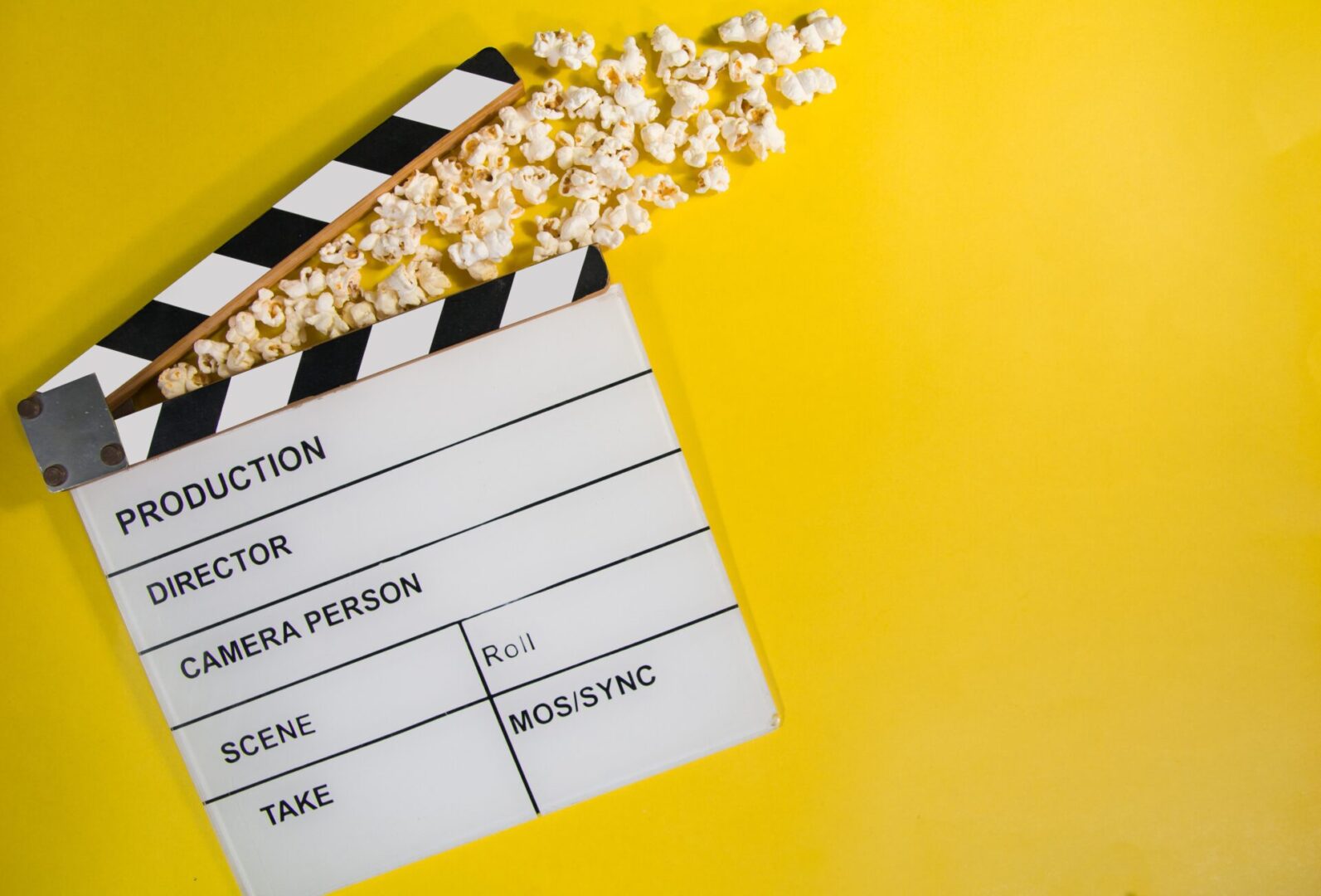 Film movie clapperboard with popcorn on vibrant yellow background